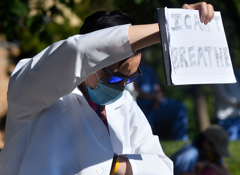 Jin Cai, a fellow in the MU School of Medicine, holds a sign during a moment of solidarity